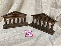 Pair of vintage cast iron Gothic building bookends with a pink lot number tag in front on a beige fabric background.
