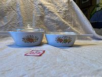 Two vintage CorningWare covered pots with Spice of Life decoration, showing front and side views with lids in place.