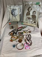 Full lot image showing two picture frames, ceramic box, and assortment of costume jewelry on cloth background.