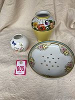 Three vintage ceramic items: Nippon sieve, Noritake vase, Ansley bud vase together on fabric