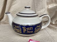 Front angle view showing the Tetley Teas logo on the blue and gold decorated teapot body.