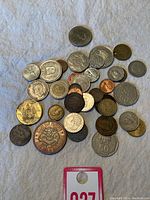 Top view of a mixed lot of 30 world coins on a textured cloth background, ranging in size, color and country of origin.