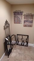 Corner display of wrought iron garden gate, round wall basket, vineyard-themed metal plaques, metal art with fish motif, and framed mirror.