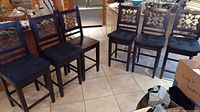 Six bar height chairs arranged in kitchen area, five have dark blue cushions, show some wear, one chair without cushion and repaired on seat.