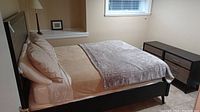 Wood bed frame set up with mattress and bedding for demonstration. Includes two matching nightstands.