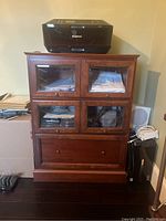 Front view of the brown wooden cabinet showing four glass front drawers and one solid wood drawer at bottom with Canon printer on top.