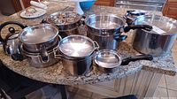 Overview of all stainless steel cookware and kettle items arranged on countertop.