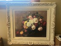 Full view of framed oil painting showing bouquet of roses and detailed cream decorative frame.