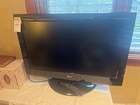 Front view of LG 32-inch TV on stand showing screen and remote on base.