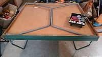 Folded ping pong table frame and underside showing metal legs and edge wear