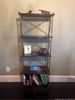 Front view of dark brown wood and metal framed shelf unit with multiple items on shelves.