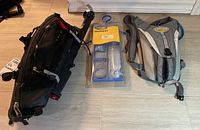 Photo of three items: black trunk bag attached to Topeak Beam Rack EX, Camelbak cleaning kit package, and grey Camelbak water backpack.