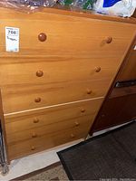 Front view of the wood dresser showing six drawers with round wooden knobs.