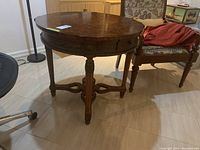 Front-left three-quarter view showing circular top and apron carving