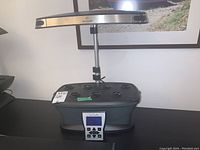 Front view of the AeroGarden grow light with seven planting holes, adjustable light stem, and control panel.