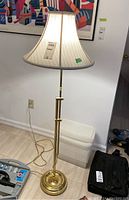 Full view of the floor lamp showing the metal base, adjustable pole, and fabric lampshade in a room context.