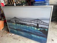 Full view of framed picture showing city skyline with bridge and water in foreground.