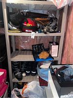 Plastic shelving unit with four shelves in a basement setting, surrounded by various items including helmets, roller skates, and boxes.