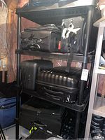 Full view of shelving unit loaded with various black suitcases showing size and shelf spacing.