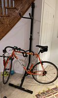 Full view of the Saris two-tier bike stand with an orange road bike hanging on it, showing overall size and design.