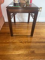 Front view of the wood end table showing the rectangular shape, dark brown finish, and decorative cut-out design on legs.
