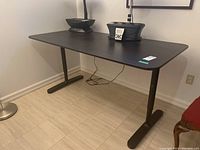 Full view of black work table with items on top showing size and surface condition.