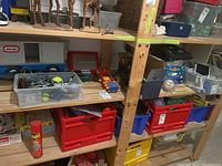 Wide view of shelf with Little Tikes camper truck, other toys and boxes.