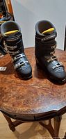 Pair of black adult Salomon Sensifit ski boots with four silver buckles, shown on brown table