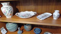 View of shelf with four china pieces: one large vase, one serving dish with handles, one rectangular tray, and one smaller vase, all in Aynsley floral and bird pattern.