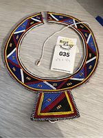 Top view of the colorful Maasai beaded African necklace laid flat, showing overall shape and string closure with shell bead.
