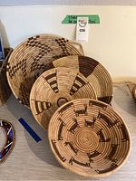 Four woven baskets displayed on a table showing size variation and pattern details from Botswana.