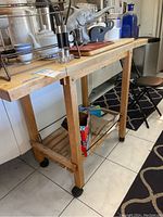 View of wooden cart with kitchenware and blue glass bottles on top and storage boxes below