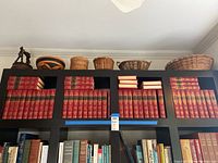 Top shelf of black cubed bookcase holding multiple red Harvard Classics volumes in four compartments