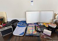 Wide view of various school and office supplies including backpacks, stationery, calculator, ledger book, and scissors.