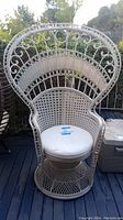 Full front view of white wicker peacock chair showing overall condition and cushion.