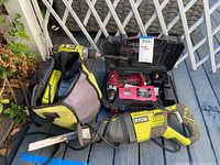 Three tools laid out on deck: Ryobi saw, two drills, bag and case