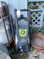 Front view of black and gray Sun Joe pressure washer with green accent and hose coiled on side.