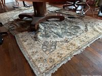 Full view of rug under table showing central medallion, border and fringe ends