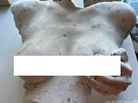 Close-up front view of the white female torso sculpture with a hand covering the right breast.