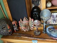 Overview of carved masks and figurines arranged on wooden shelf