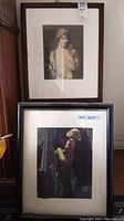 Two framed prints stacked against wall, one art shows woman in vintage clothing, other shows woman with flowers in hair; one frame incomplete