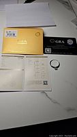 Photo showing the ring, certification card, grading report, and gold GRA box.