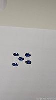 Five natural royal blue kyanite gemstones laid out on a white background showing pear shape and clarity.