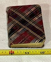 Closed book showing red, black, and cream plaid cover with size measurement.