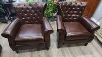 Both brown tufted armchairs placed side by side in room