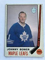 Front side of the card showing Johnny Bower in blue Maple Leafs uniform with team logo, player name, position, and hockey stick graphic