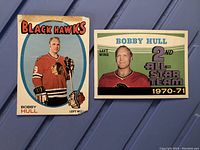Front view of two 1971-72 OPC Bobby Hull hockey cards showing one in Black Hawks uniform and one as 2nd All-Star Team with red background