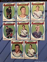 Front view of eight 1971-72 O-Pee-Chee New York Rangers hockey cards featuring player images and team logos.