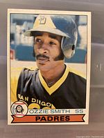 Front image of 1979 OPC Ozzie Smith baseball card depicting player portrait in Padres uniform and helmet, with name and position.