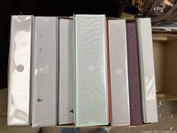 Top view of the binder spines showing different colors and sizes, all with round holes on the spine for easy handling.